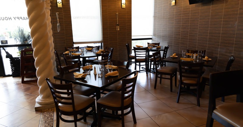 Interior with tables set for dining, a twisted column and window shades, tile flooring
