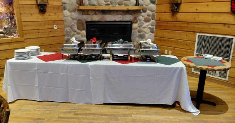 Buffet table setup with chafing dishes and fireplace in the background