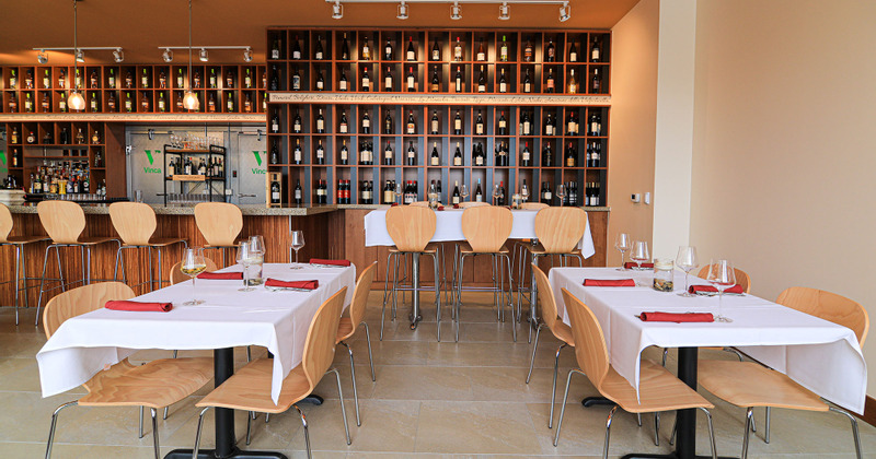 Interior, tables ready for guests, shelves with bottles of wine in the back