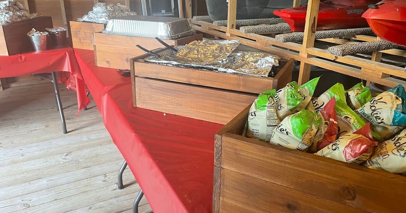 Buffet table with food trays and assorted potato chips in wooden boxes