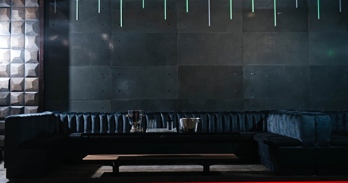 Interior, large lounge booth with low table, concrete walls with subtle neon lighting