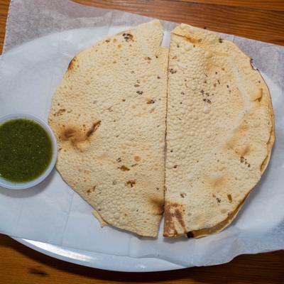 Two papads with dipping sauce on a plate.