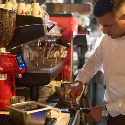 Barista preparing espresso at a coffee machine.