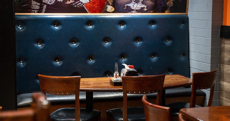 Restaurant booth with dark blue tufted seating, wooden table, and chairs
