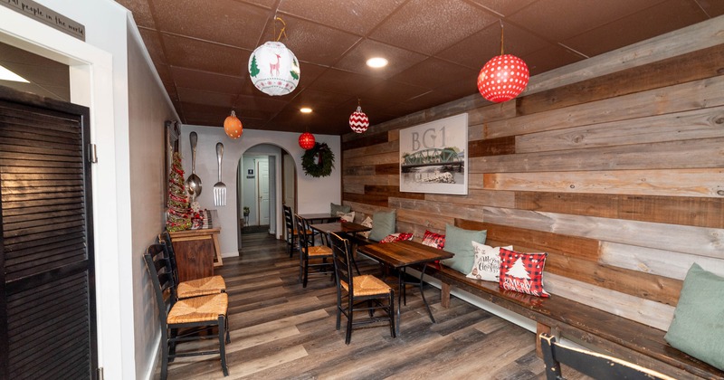 Dining area with wooden benches, festive cushions, a Christmas tree, and decorative orbs