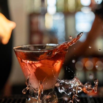 Cocktail in a martini glass splashing over the bar counter.
