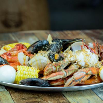 Seafood platter with lobster, mussels, potatoes, and corn on the cob.