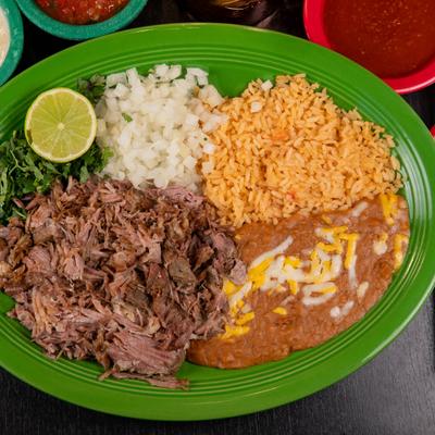 Slowed cooked pork served with rice, refried beans, onion, cilantro, and lime.