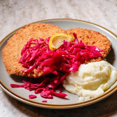 Pork schnitzel served with mashed potatoes and braised red cabbage.