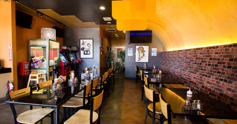 View of dining tables and seating, TVs and pictures, arcade machines by a wall