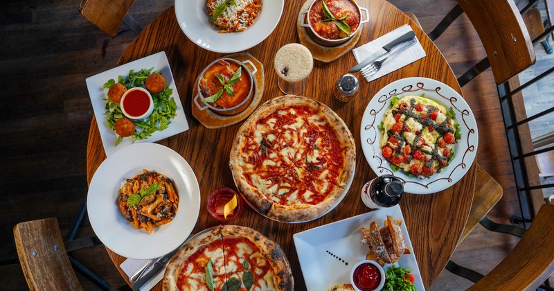 A table with multiple dishes on it including pizza, pasta, and salad