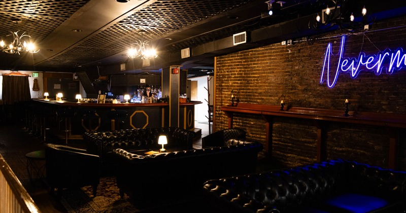 Dimly lit lounge with black leather seating
