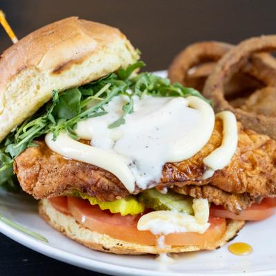 Spicy chicken sandwich served with onion rings.