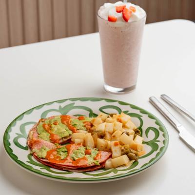 Ham and cheese tortilla melt with avocado spread and potatoes served with a strawberry milkshake.