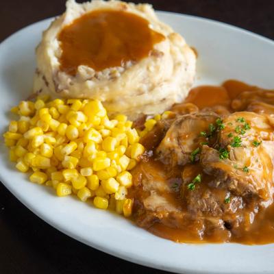Slow roasted pork served with gravy, mashed potatoes and sweet corn.