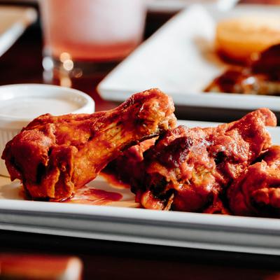 Buffalo chicken wings with a cup of dipping sauce.