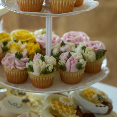 A tiered stand filled with cupcakes decorated with intricate frosting flowers.