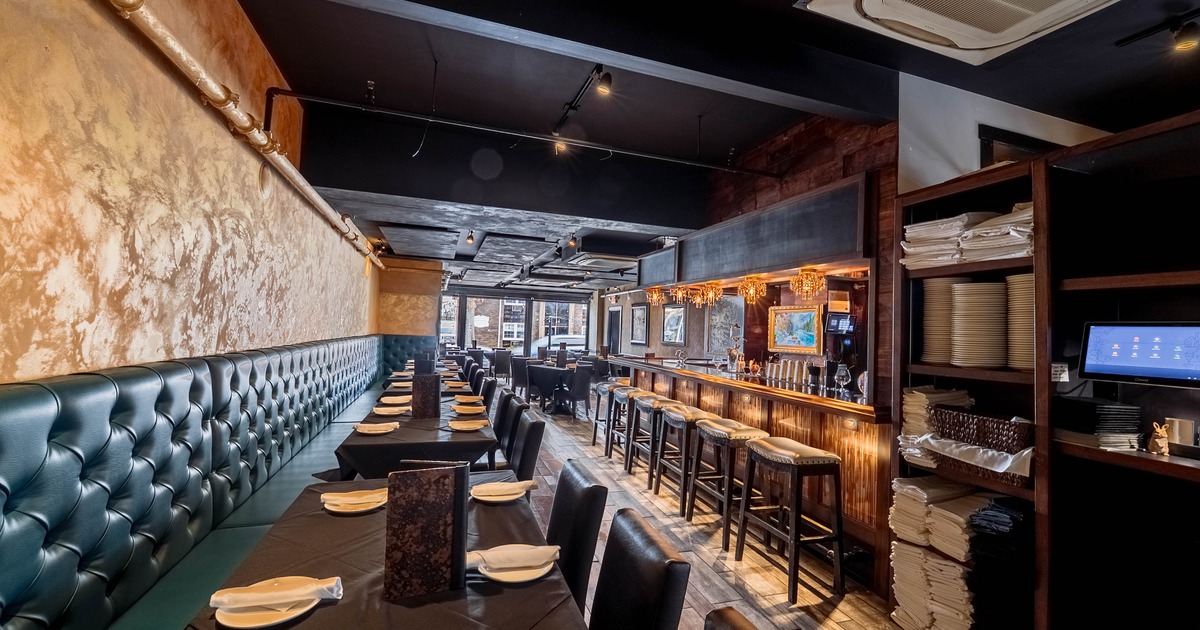 A stylish interior - green leather benches, black tablecloths and a wooden bar with cushioned stools