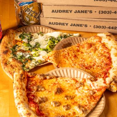 Three slices of pizza sit on a table next to pizza boxes.