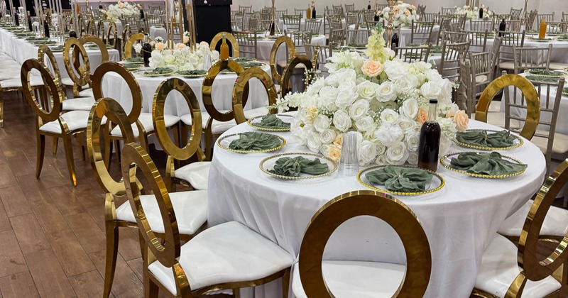 Elegant wedding table setup with gold chairs and white floral centerpieces
