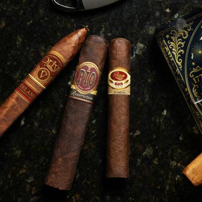 Three premium cigars resting on a dark surface.