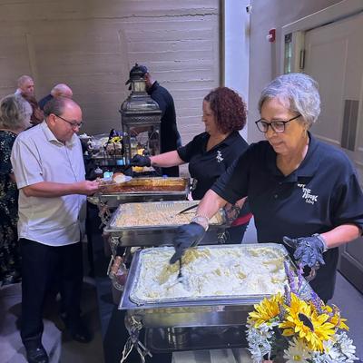Staff serving food to guests at a catered event.