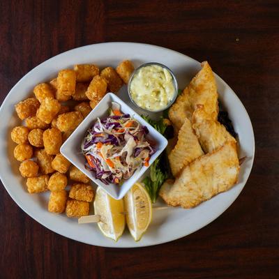 Fried cod and tater tots, served with slaw, tartar sauce, and lemon wedges, top view.