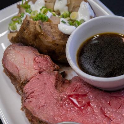 Smoked prime rib, with a loaded baked potato, and BBQ sauce.
