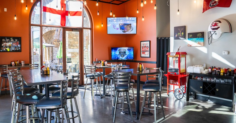 Seating tables with bar stools, TV screens on the walls