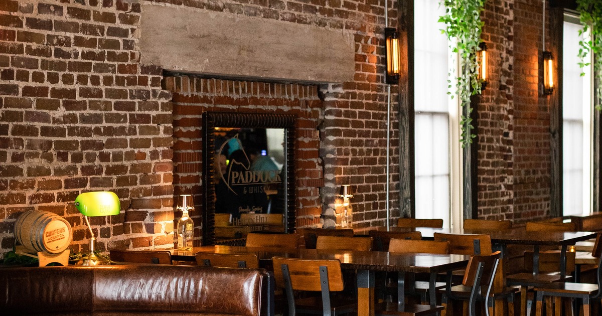 Restaurant interior with brick walls, leather booth seating, and high-top tables