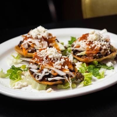 Stuffed tostadas topped with sauce, cabbage and crumbled cheese.