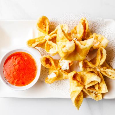 Fried Crab Rangoon served with sweet chili sauce, top view.