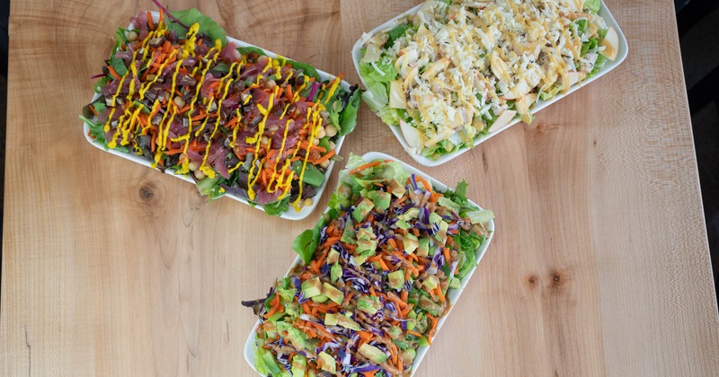 Three different salad meals served on the table, overhead view