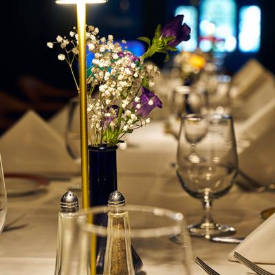 Floral centerpiece on a dressed dining table with glasses, napkins, and plates.