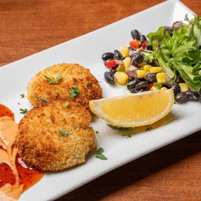 Maryland Crabcakes with black bean and grilled corn salsa and a lemon wedge.