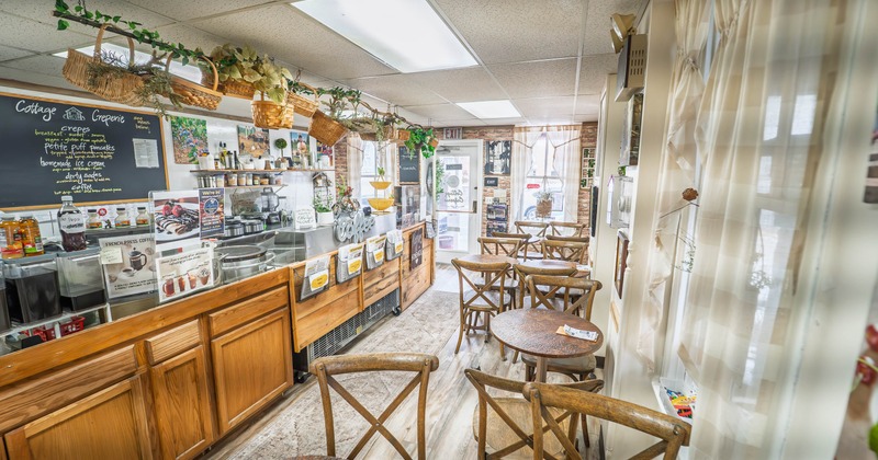 Interior of a cozy café with wooden furniture and hanging basket decorations.