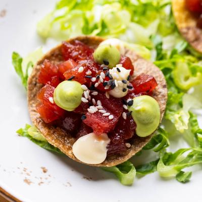 Tuna tostada with sesame seeds, mayo, and avocado sauce.