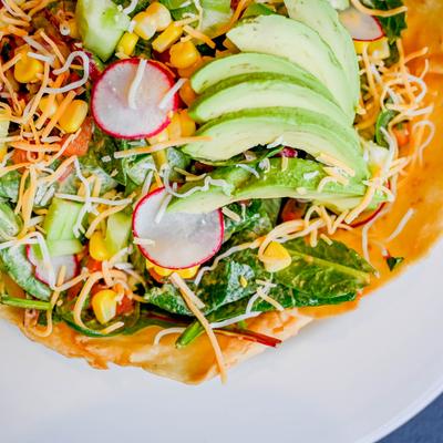 Salad in a tortilla bowl, with greens, pico, cheddar, radish, avocado, and chipotle lime sauce.