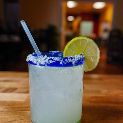 Margarita served in a glass with salt rimmed rim, and a lime slice.