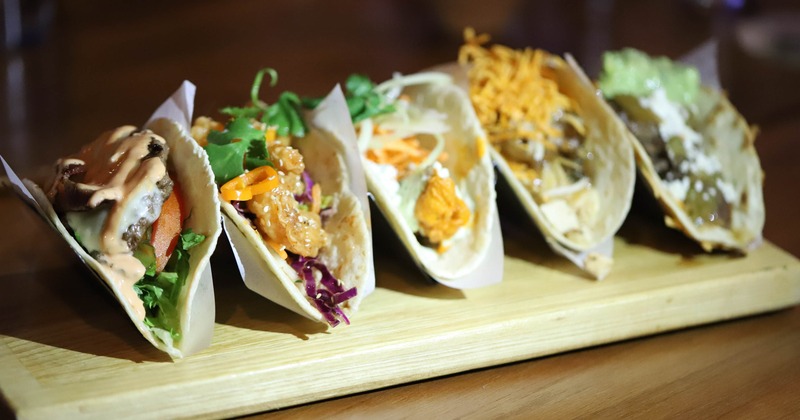 Various tacos served on a wooden board