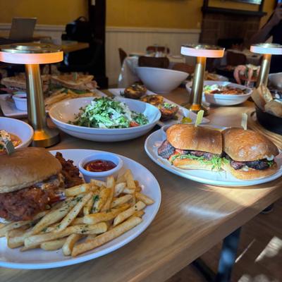 Restaurant table filled with burgers, fries, fresh salads, and sandwiches.