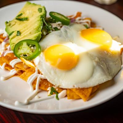 Chilaquiles topped with sunny side up eggs, avocado, and jalapeno slices.