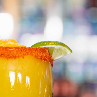 Mango By The Sea cocktail with tajin rim and lime garnish.
