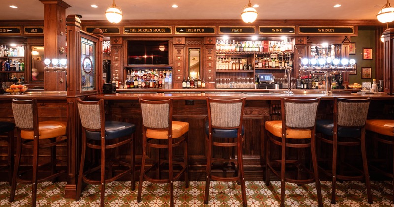 Interior, bar area, wooden top bar with bar stools, wooden drink shelves, tile flooring