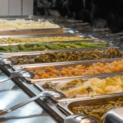 Buffet line with metal trays of vegetables and side dishes.