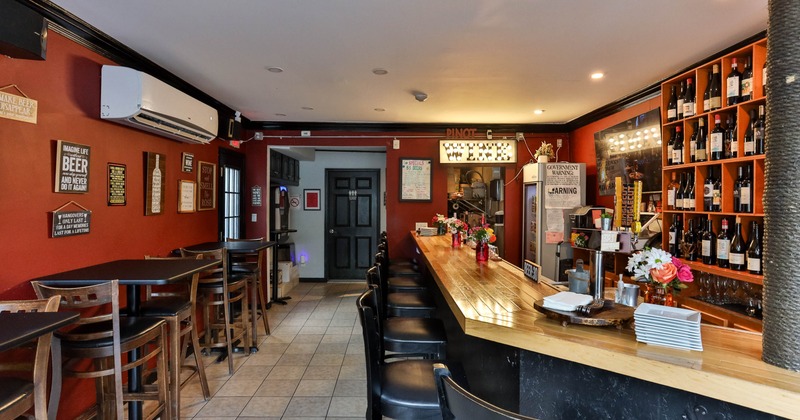 Interior seating area with a long wooden counter, and black stools