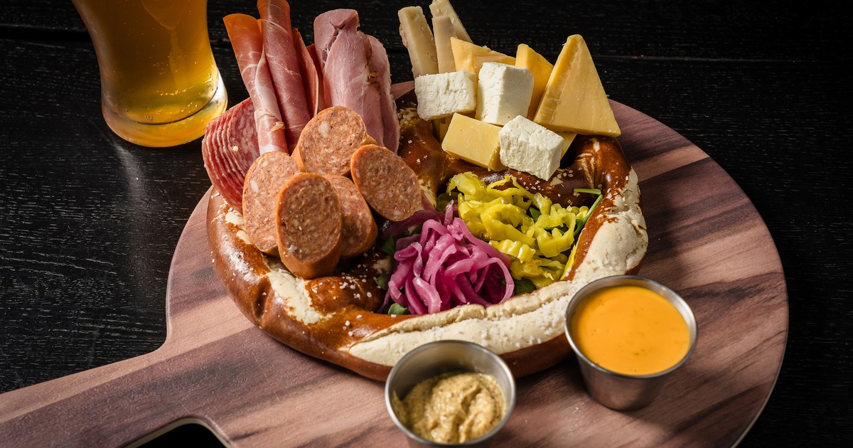 Loaded Pretzel with cured meats, cheeses, pickles, and dips on the side