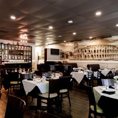 Interior with a distinct mural of the Roman Colosseum, table seating and a bar area.