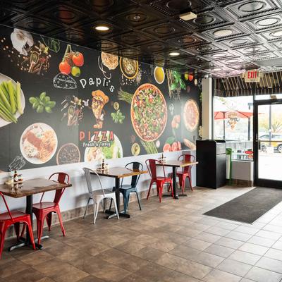 Interior with tables, chairs, and a pizza-themed mural.