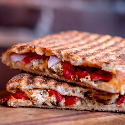 Grilled panini sandwich with melted cheese and peppers.